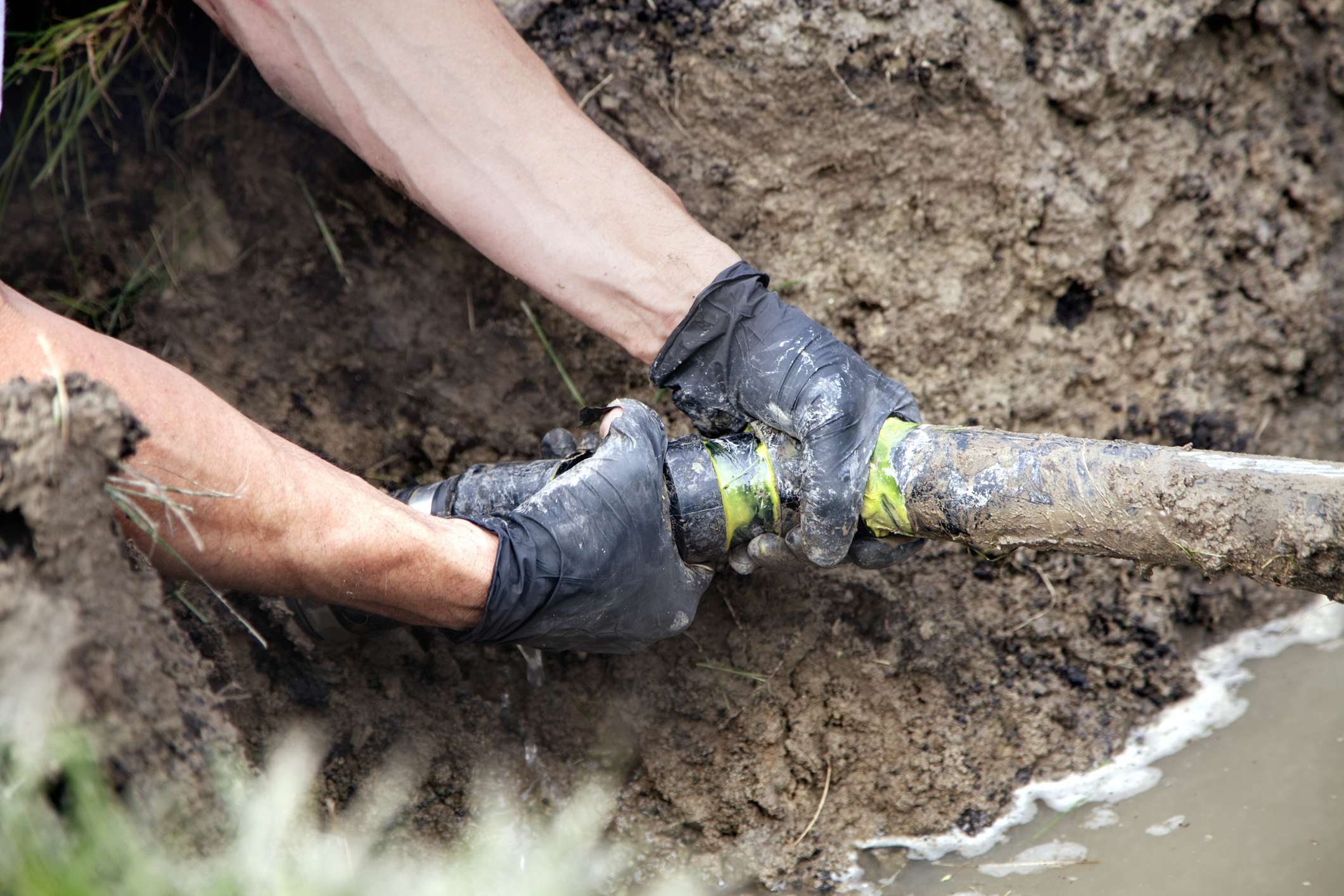 an engineer with gloves repairing a drain in wigan
